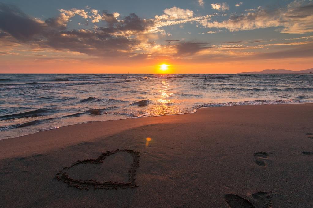 on Christian marriage heart on sand with sunset in background