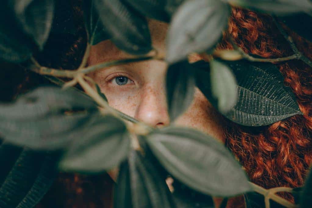 man hiding behind leaves